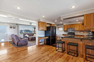 Kitchen featuring sink, light hardwood / wood-style flooring, a kitchen breakfast bar, kitchen peninsula, and stainless steel appliances