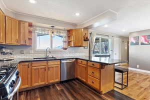 Kitchen with sink, a breakfast bar, appliances with stainless steel finishes, hanging light fixtures, and kitchen peninsula