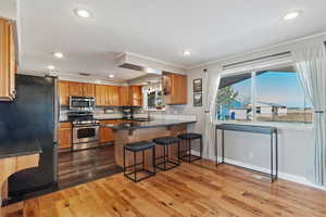 Kitchen featuring a kitchen bar, sink, appliances with stainless steel finishes, kitchen peninsula, and hardwood / wood-style flooring