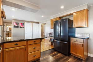 Kitchen featuring black refrigerator, dark stone countertops, and dark wood-type flooring