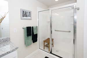 Bathroom featuring vanity, a shower with door, and tile patterned floors