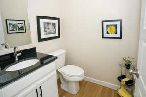 Bathroom with hardwood / wood-style flooring, vanity, and toilet