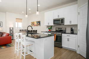 Kitchen featuring sink, a center island with sink, white cabinets, and appliances with stainless steel finishes