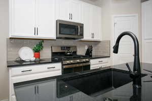 Kitchen with white cabinetry, sink, tasteful backsplash, and stainless steel appliances