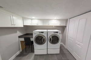 Clothes washing area with washer and dryer and a textured ceiling