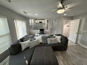 Living room with hardwood / wood-style floors, a textured ceiling, and ceiling fan