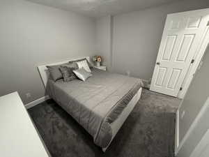 Bedroom featuring dark carpet and a textured ceiling