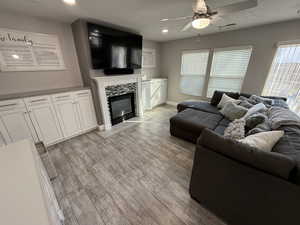 Living room with ceiling fan, a textured ceiling, and light hardwood / wood-style floors