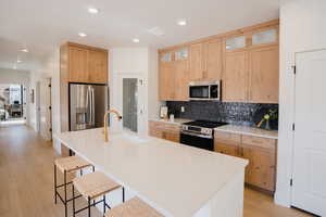 Kitchen featuring stainless steel appliances, a kitchen breakfast bar, sink, and a center island with sink