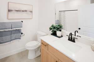 Bathroom with a shower with curtain, vanity, tile patterned floors, and toilet