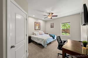 Bedroom with light carpet, ceiling fan, and a textured ceiling