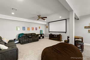 Carpeted cinema room featuring ceiling fan