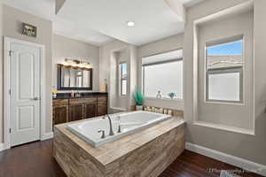 Bathroom featuring tiled tub, wood-type flooring, and vanity