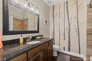 Bathroom with walk in shower, vanity, toilet, and hardwood / wood-style floors