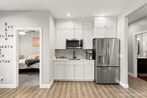 Kitchen featuring sink, light hardwood / wood-style floors, white cabinets, and appliances with stainless steel finishes