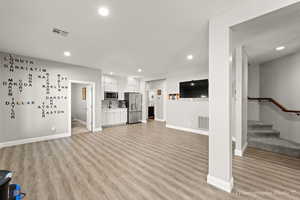 Unfurnished living room featuring sink and light hardwood / wood-style flooring