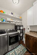 Clothes washing area with cabinets, washing machine and dryer, dark hardwood / wood-style floors, and a textured ceiling