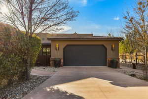 View of front of home with stucco siding, a tiled roof, a chimney, and concrete driveway