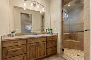 Bathroom featuring tile patterned floors, a shower with door, and vanity