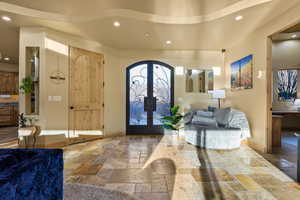 Entrance foyer featuring stone tile floors, recessed lighting, arched walkways, french doors, and baseboards
