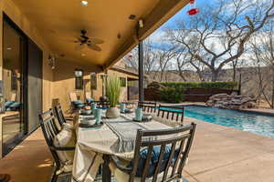 View of patio with a fenced in pool, pool water feature, and ceiling fan