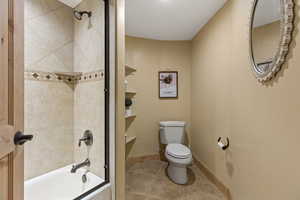 Bathroom featuring tiled shower / bath, tile patterned floors, and toilet