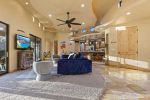 Living room with plenty of natural light, a towering ceiling, and ceiling fan