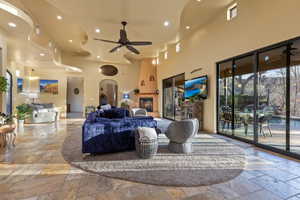 Living room with a towering ceiling, a large fireplace, and ceiling fan