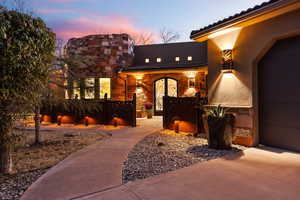 Exterior entry at dusk featuring stucco siding, a tiled roof, and stone siding