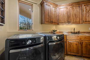 Clothes washing area featuring cabinets, independent washer and dryer, and sink