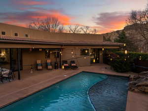 Pool at dusk featuring a patio