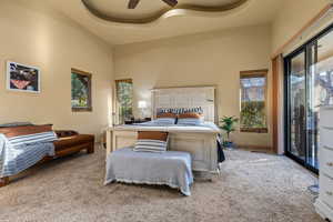 Bedroom with light carpet, a high ceiling, access to exterior, a ceiling fan, and baseboards