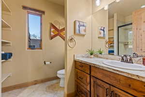 Bathroom featuring vanity, toilet, an enclosed shower, and tile patterned flooring