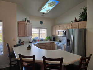 Kitchen featuring light brown cabinetry, sink, a kitchen breakfast bar, kitchen peninsula, and stainless steel appliances