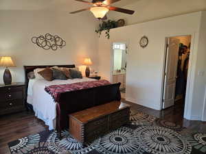 Bedroom featuring dark wood-type flooring, ceiling fan, ensuite bathroom, and a spacious closet