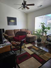 Living room with hardwood / wood-style flooring, ceiling fan, vaulted ceiling, and a textured ceiling