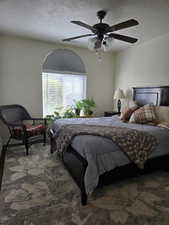 Bedroom featuring ceiling fan, carpet floors, and a textured ceiling