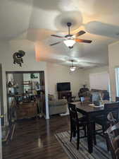 Dining room with ceiling fan, lofted ceiling, dark hardwood / wood-style floors, and a textured ceiling