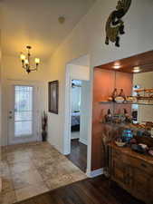 Foyer with lofted ceiling, light wood-type flooring, and an inviting chandelier