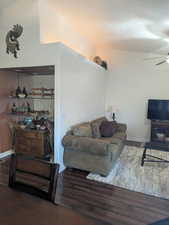 Living room with vaulted ceiling, ceiling fan, and hardwood / wood-style floors