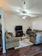 Living room with ceiling fan, dark wood-type flooring, and a textured ceiling