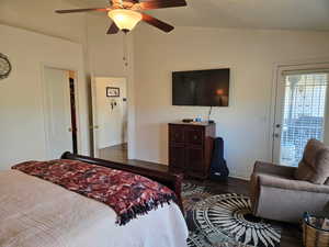 Bedroom with dark hardwood / wood-style flooring, vaulted ceiling, ceiling fan, and access to outside