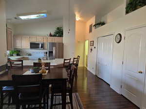 Dining space with dark hardwood / wood-style floors and high vaulted ceiling