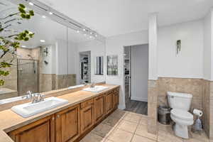 Primary Bathroom with vanity, toilet, an enclosed shower, and tile walls