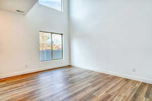 Empty room featuring light hardwood / wood-style floors and a high ceiling