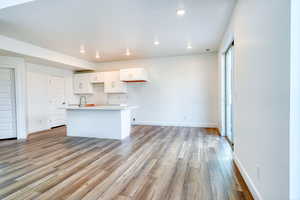 Kitchen featuring white cabinetry, sink, a kitchen island with sink, and light hardwood / wood-style flooring