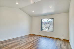 Empty room with lofted ceiling and light hardwood / wood-style floors