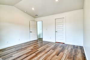 Unfurnished bedroom featuring vaulted ceiling, dark hardwood / wood-style floors, and a closet