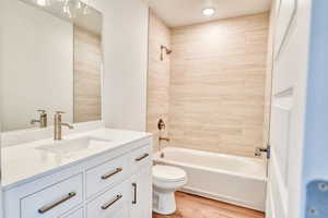 Full bathroom with wood-type flooring, tiled shower / bath, vanity, and toilet