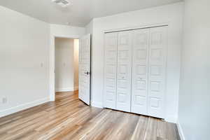 Unfurnished bedroom with light hardwood / wood-style flooring and a closet